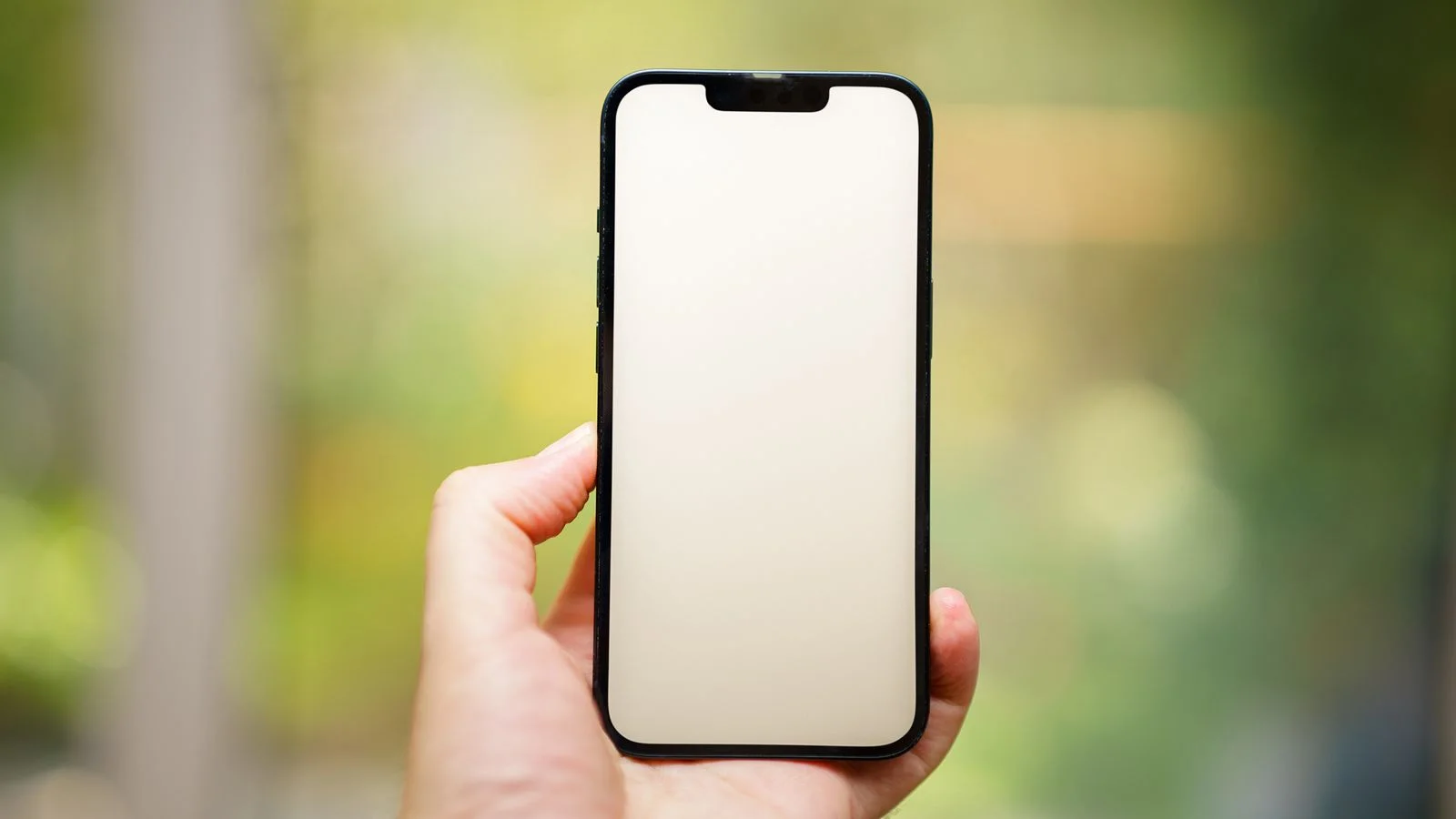 Mão segurando smartphone com a tela em branco, representando celular lento e travando