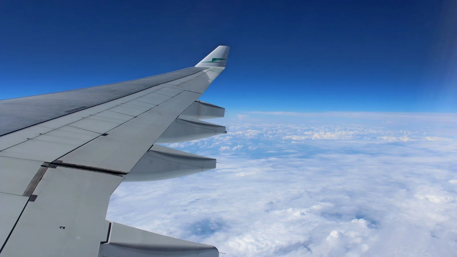 Asa de avião em voo acima das nuvens com céu azul