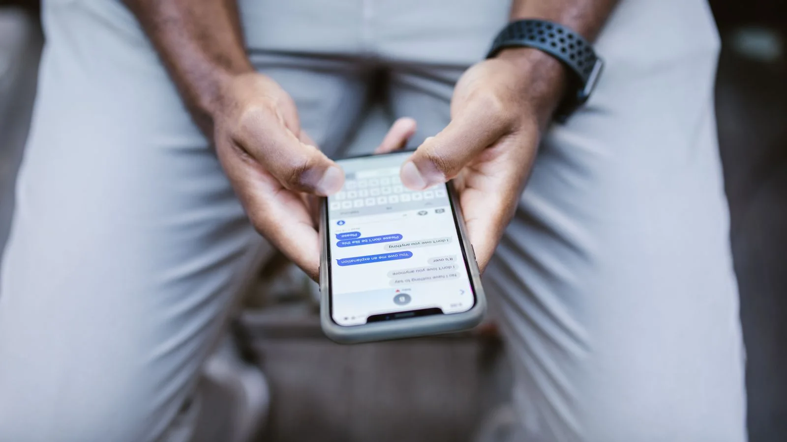 Close dos polegares de um homem digitando uma mensagem no smartphone