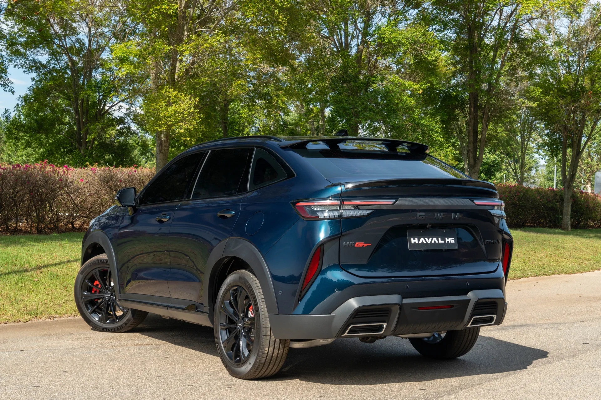 Traseira do GWM Haval H6 GT Flex azul em três quartos de traseira, com aerofólio no teto e para-choque esportivo