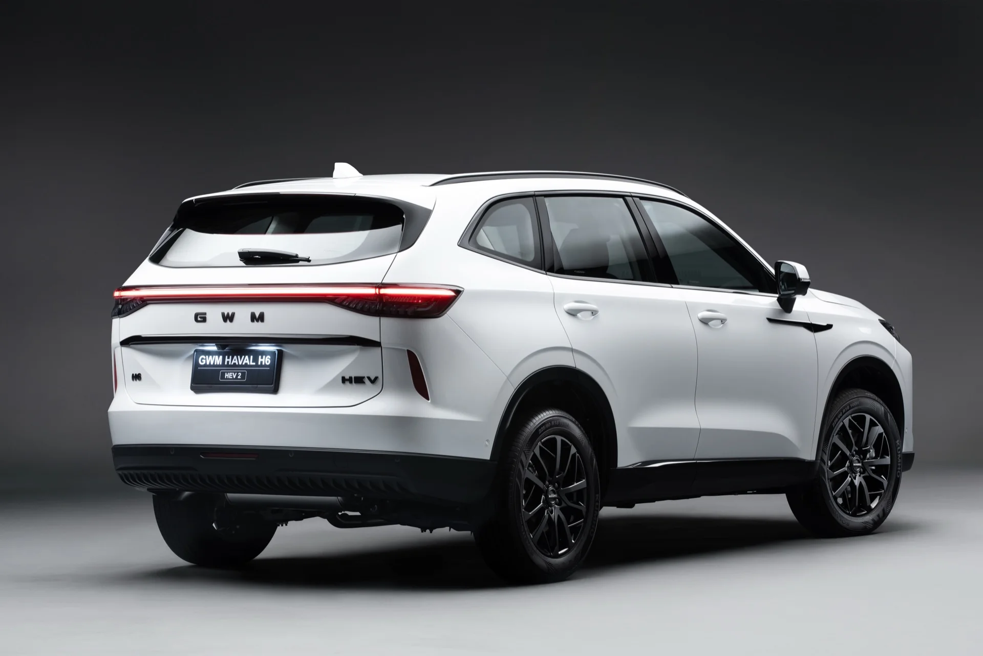 Traseira do GWM Haval H6 HEV2 branco em estúdio, com a barra de luz entre as lanternas e o emblema HEV