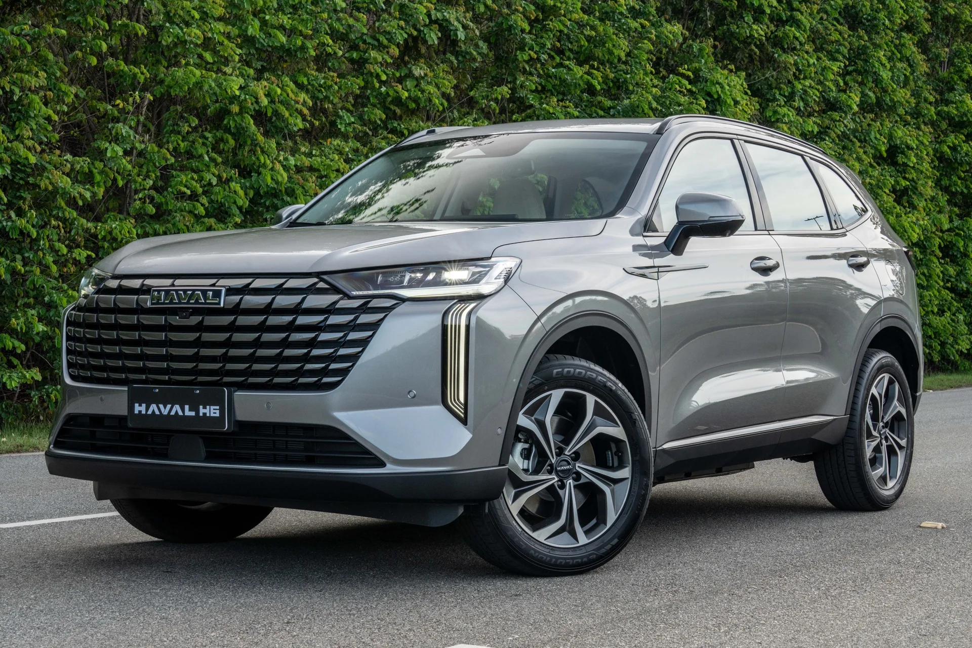 GWM Haval H6 PHEV35 Flex cinza visto de frente, em ângulo de três quartos, parado em uma via com cerca viva ao fundo