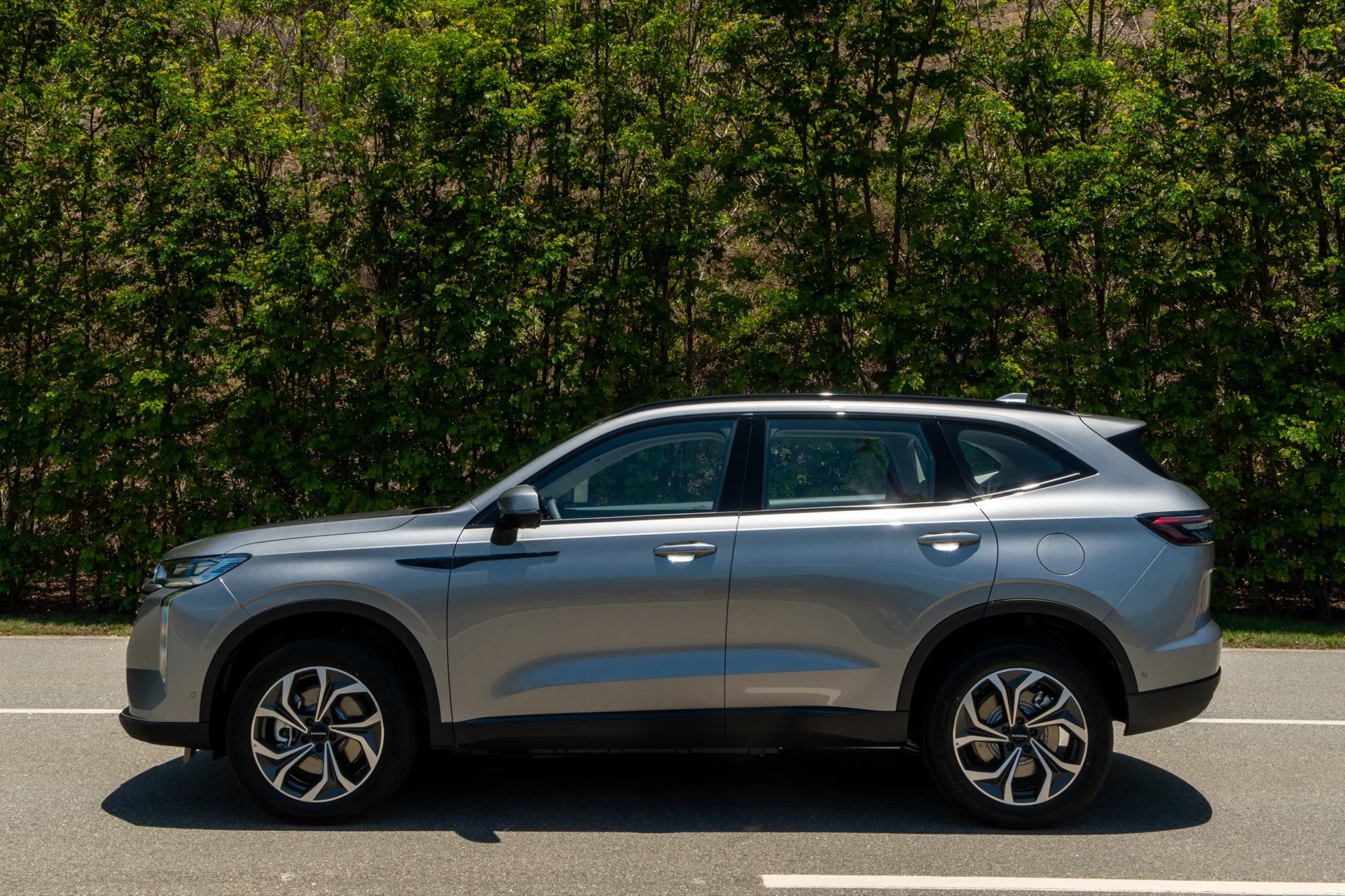 Lateral do GWM Haval H6 PHEV35 Flex cinza em uma via asfaltada