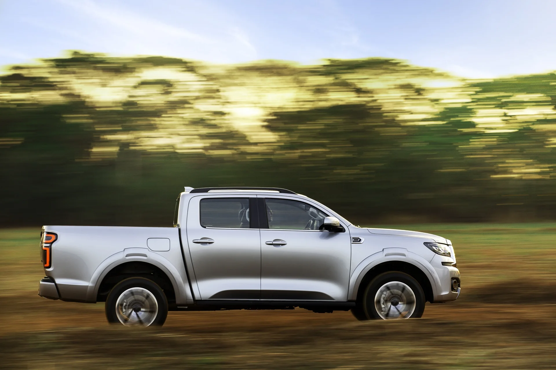 Lateral da GWM Poer P30 prata em movimento em uma estrada de terra