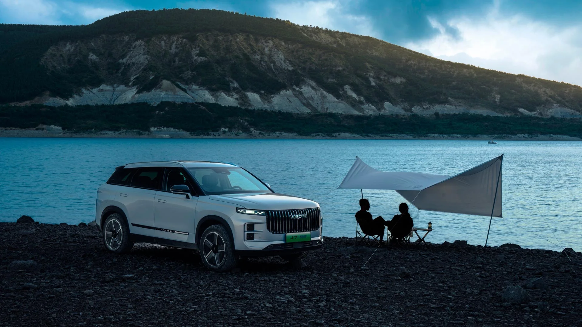 Jaecoo 7 branco estacionado à beira de um lago, ao lado de um toldo de acampamento
