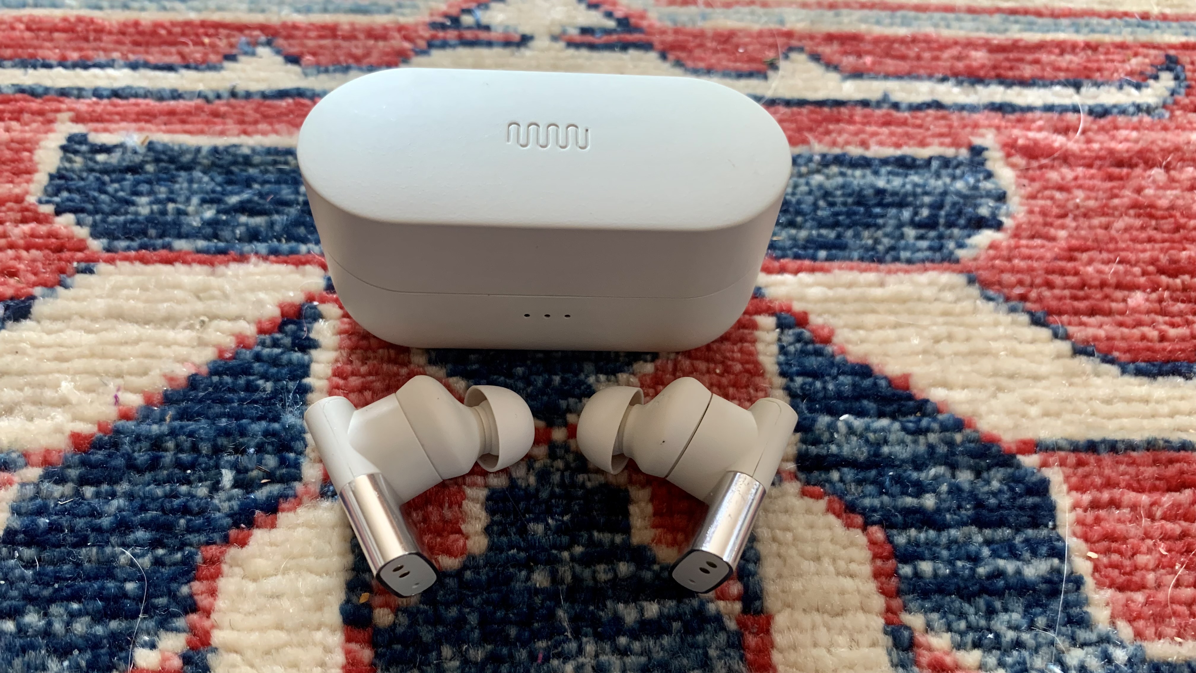 Status Between 3ANC earbuds out of their case, on colorful background